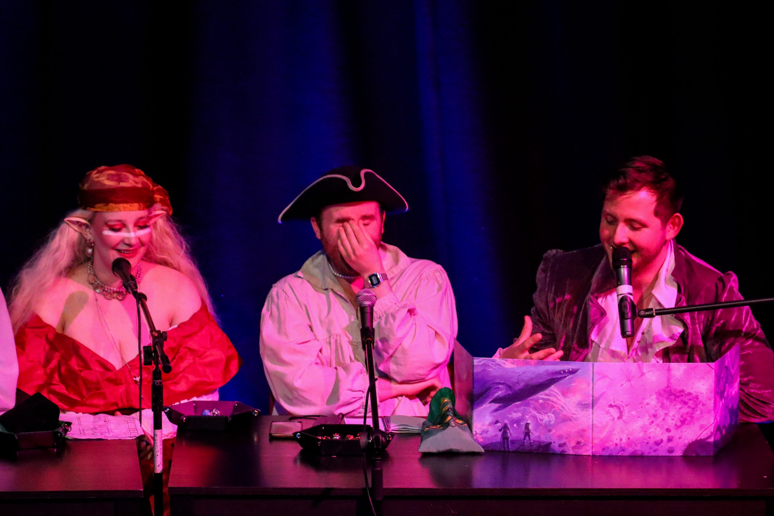 Three Dungeons and Dragons players at a table, dressed up in pirate themed-costumes.