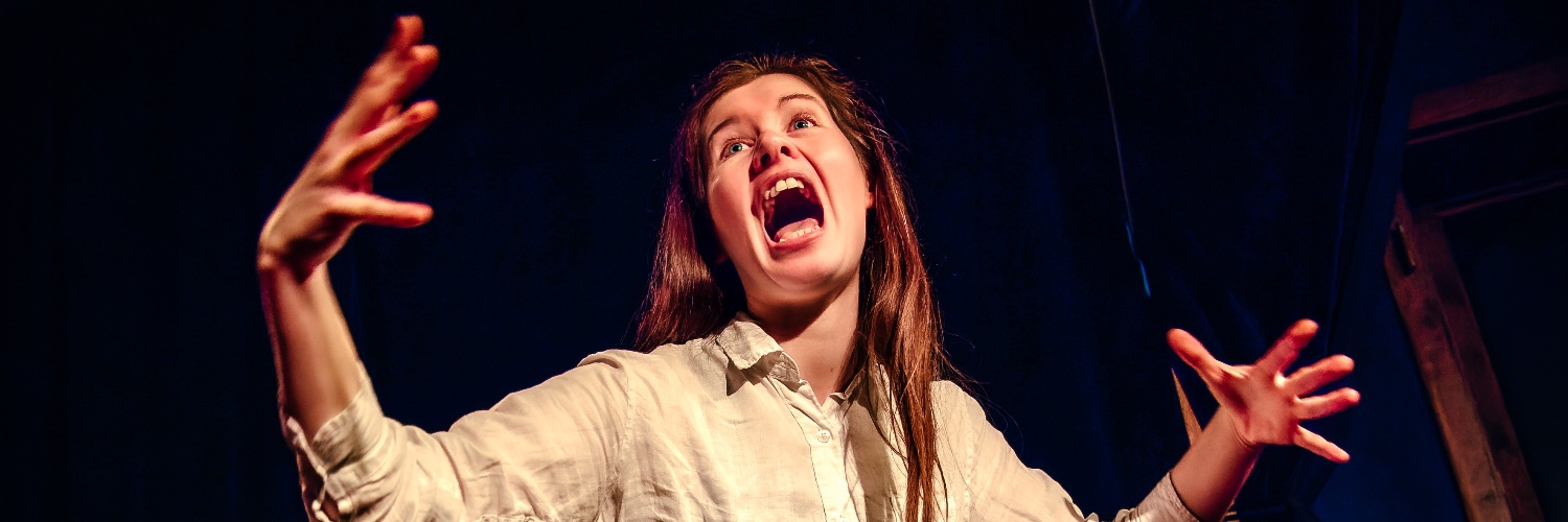Sinéad O’Brien in a white shirt, arms outstretched, seemingly screaming.