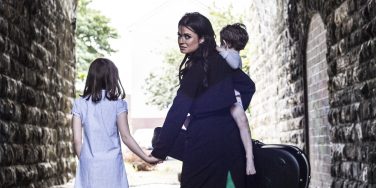 A woman with children and a guitar in a short tunnel.