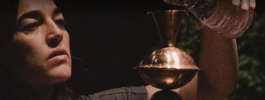 A person pouring water into a copper vessel.