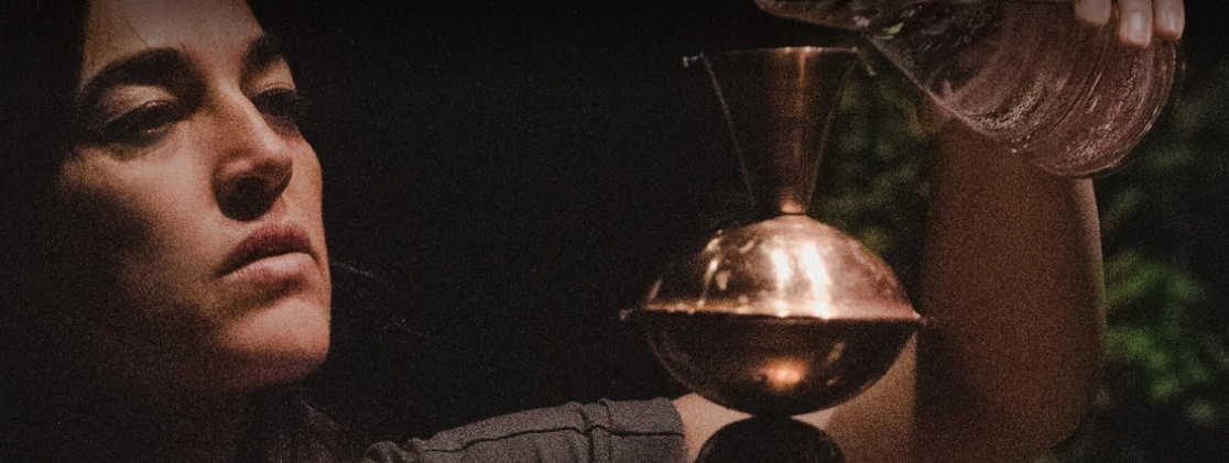 A person pouring water into a copper vessel.