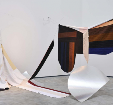 Structural art piece featuring hanging fabric and paper from the art exhibition of Claire Barclay and Oana Stanciu.