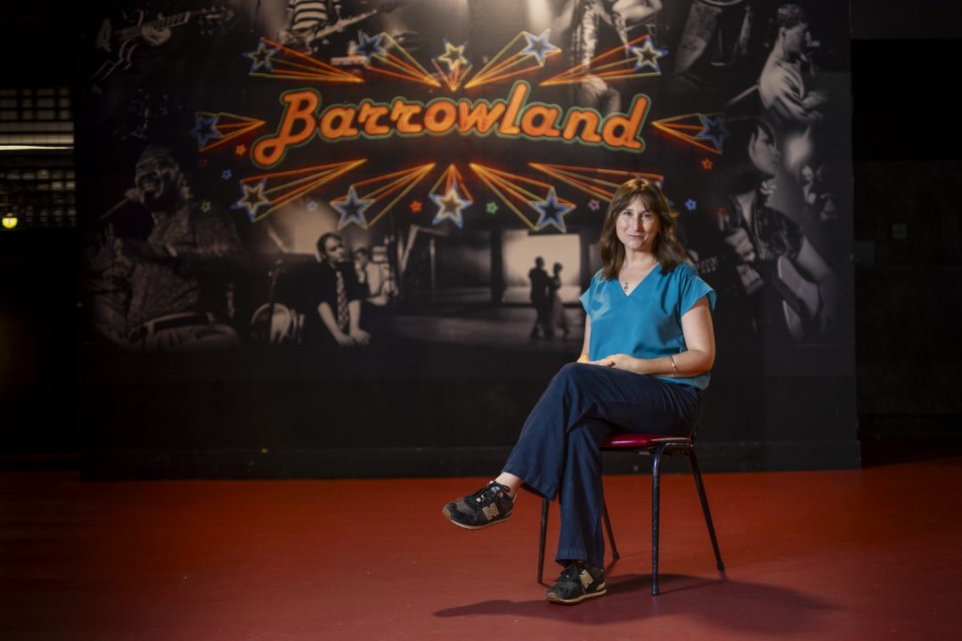 Alison Irvine seated in front of a mural of Glasgow's Barrowland ballroom