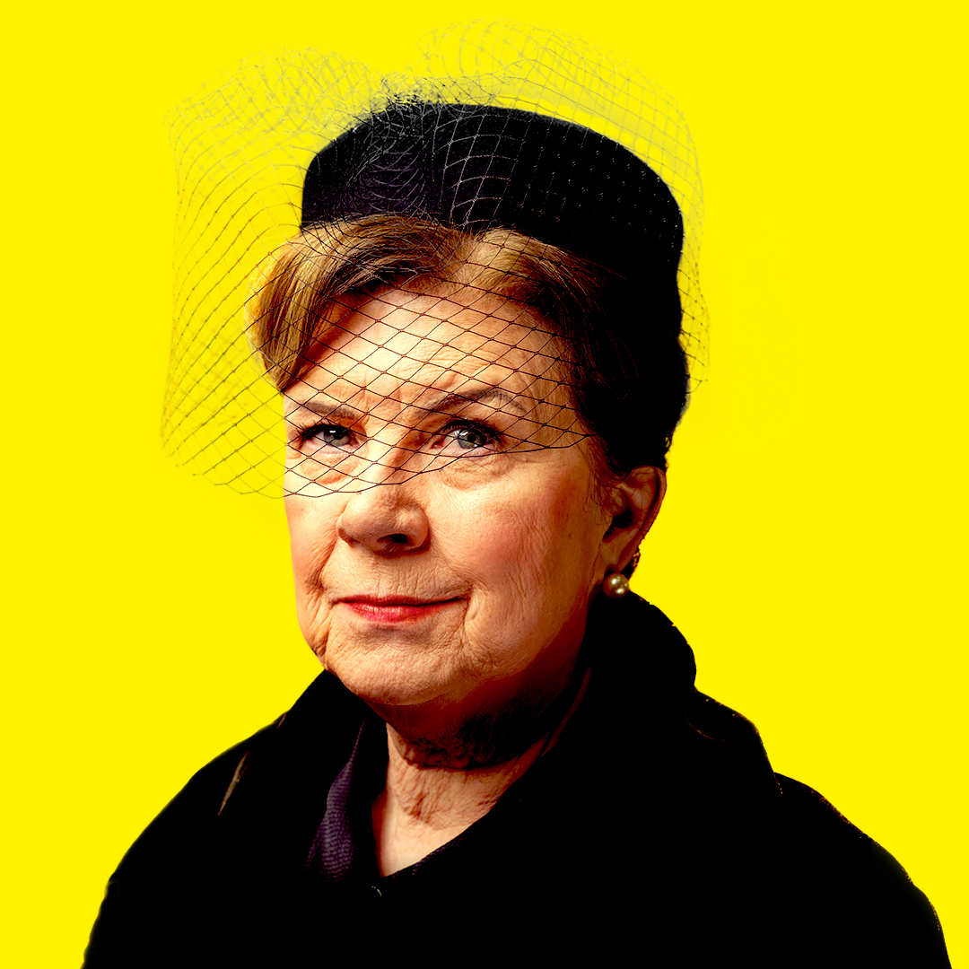 A striking portrait of actress Elaine C. Smith wearing a black hat and veil against a solid yellow background for Cathy.