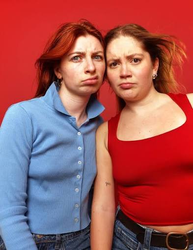 Two woman stood against a red-coloured background for Edinburgh Fringe show Clary.