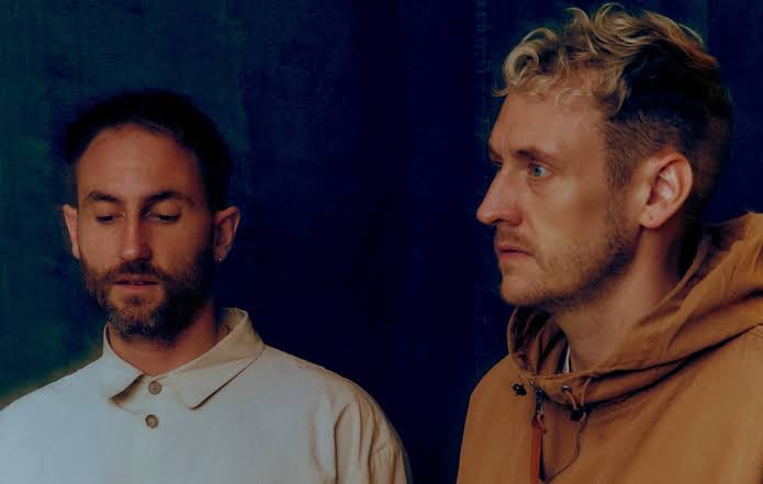 A close-up portrait photograph of the electronic duo Maribou State against a dark, textured blue background, representing one of the top music highlights at the Edinburgh Fringe.