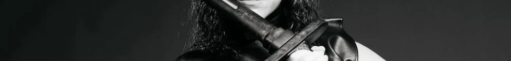 A black-and-white promotional photo of an actor in a leather costume wielding a sword for Macbeth.