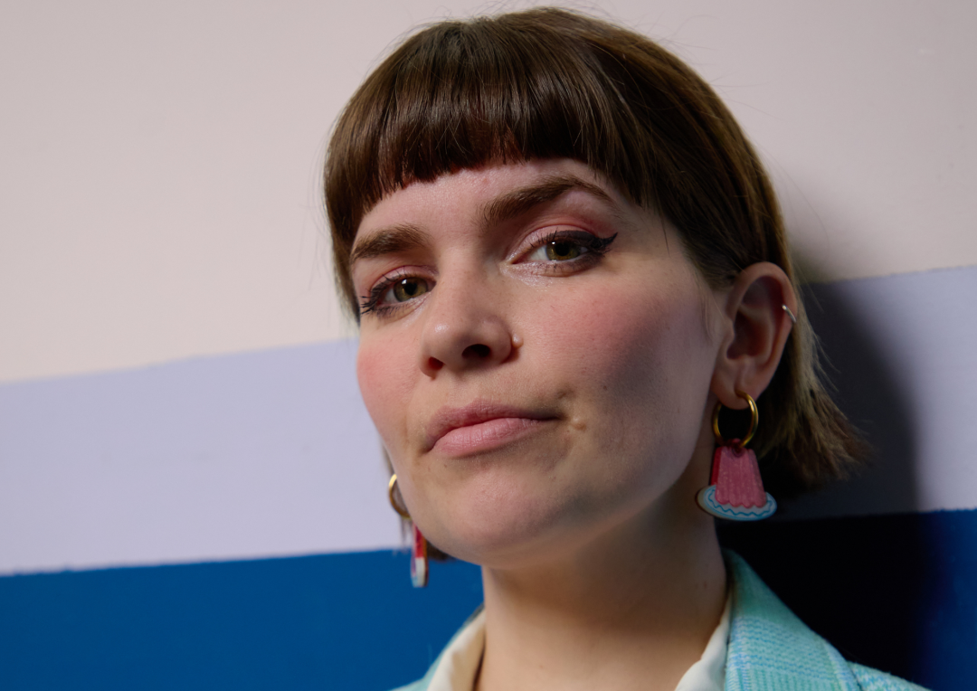 Close-up portrait of comedian Kate Hammer wearing pink earrings ahead of her Fringe debut.