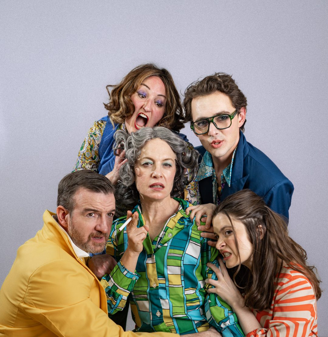 A cast of five actors in retro 1970s attire posing with dramatic expressions around a central character styled like an older glamorous star holding a cigarette.