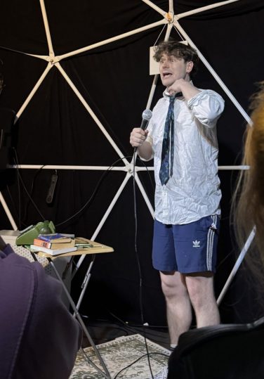 Comedian Alex Kitson performing his show 'Now Look Here' on stage inside the Big Yurt at Hoots, Potterrow during the Edinburgh Fringe.
