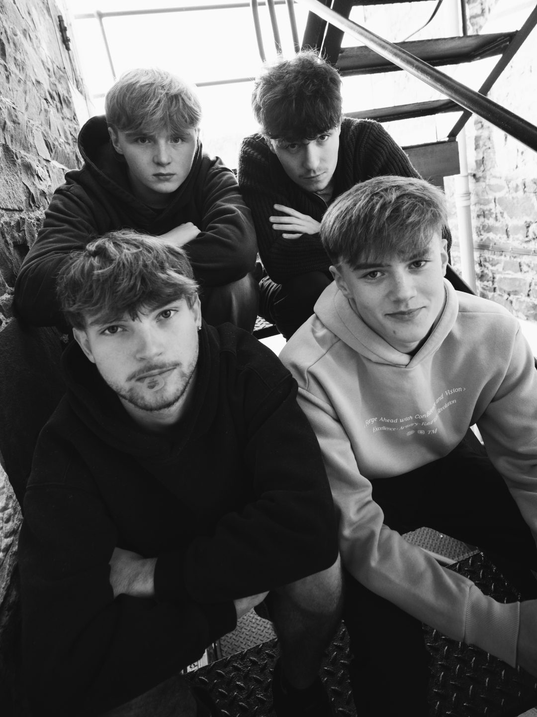 Black and white portrait of the four members of Blanc grouped together on a metal staircase.